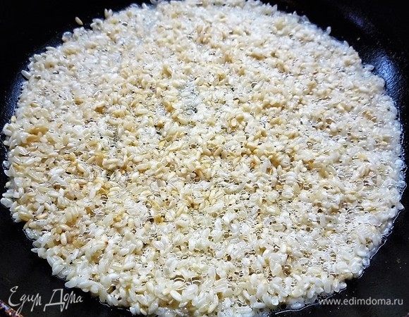 В глубокой сковороде с толстыми стенками растапливаем сливочное масло, всыпаем рис и обжариваем, постоянно помешивая, в течение 5 минут до полупрозрачности.