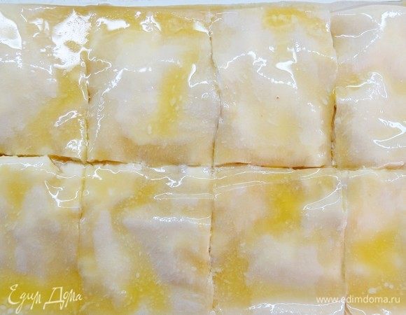 Равномерно поливаем растопленным сливочным маслом разрезанную на квадраты баницу. 