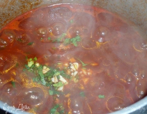 Добавляем чеснок и зелень в суп. Солим по вкусу. Перемешиваем. Убираем кастрюлю с огня.