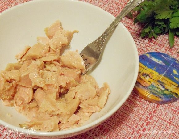 Консервированного тунца выложить в миску, добавить столовую ложку оливкового масла из банки и слегка измельчить вилкой.