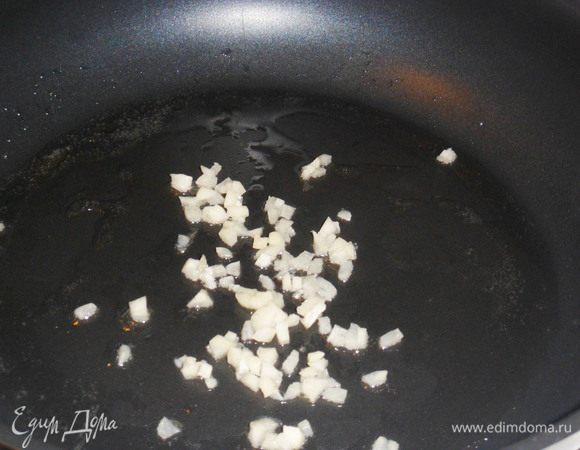 На сковороду налить столовую ложку оливкового масла из заливки тунца, обжарить чайную ложку измельченного чеснока, не доводя до изменения его цвета.