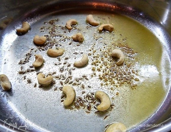 В глубокой сковороде разогреваем сливочное масло, высыпаем кумин, зерна горчицы и орешки кешью. Все перемешиваем и обжариваем в течение 1 минуты.