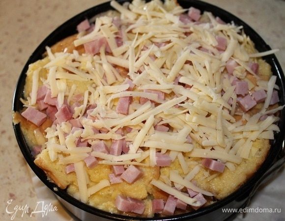 Форму (d=18 см) застелить пергаментом (дно и бока), смазать 1 ст. л. растительного масла, выложить содержимое пакета, утрамбовать рукой. Сверху посыпать оставшимся сыром и ветчиной, нарезанной кубиками.

