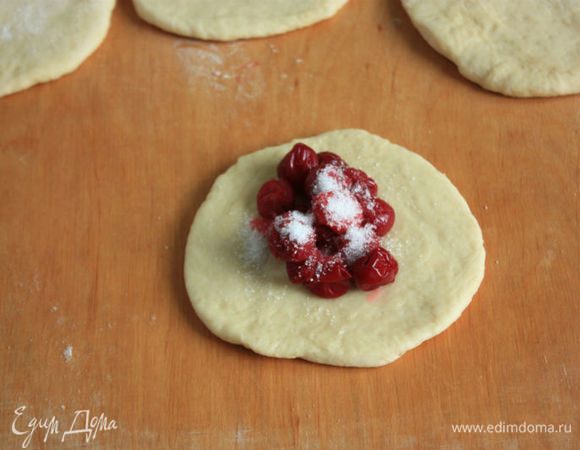 В центр каждого кружочка положить вишню (много) и посыпать сахаром на свой вкус. Сок не должен попадать в пирожки. Соединить плотно края теста и выложить пирожки в противень швом вниз.