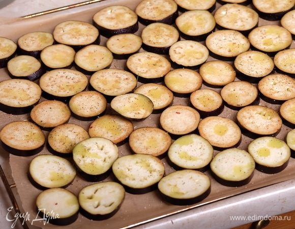 Баклажаны помыть и нарезать ломтиками толщиной примерно 5 мм. Выложить их на противень, застеленный пергаментом. Сбрызнуть каждый ломтик небольшим количеством оливкового масла (у меня специальный распылитель для масла, можно смазывать силиконовой кисточкой), посыпать небольшим количеством специй (можно использовать французские или итальянские травы, или на свой вкус).