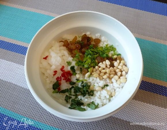 Смешаем рис, лук, изюм, кедровые орехи, мяту и петрушку. Добавим по вкусу соль и перец чили. Перемешаем.