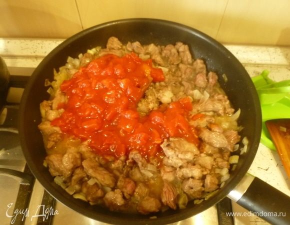 Добавить томаты. Влить часть бульона, чтобы мясо было полностью покрыто, тушить на слабом огне 1 час.