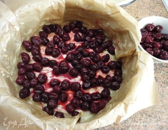 Примерно горсть вишни отложите, а оставшуюся вместе с соком выложите на дно формы.