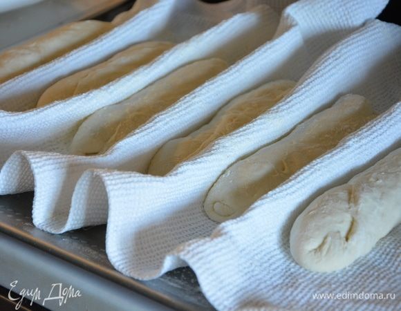 Полотенце присыпать мукой, выложить хлеб на полотенце швом вверх, сделать бортики между хлебушками.