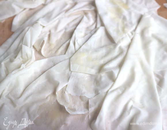 Растопить сливочное масло. Листочки фило положить на рабочую поверхность, расположив их неравномерно (складками). Смазать кисточкой слегка маслом.