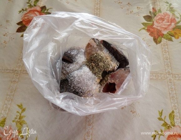 Складываем куски рыбы в полиэтиленовый пакет. Добавляем 1/2 ст. л. соли и 1/2 ч. л. чабера. Хорошо распределяем соль и ароматную сушеную зелень, предварительно завязав пакет.