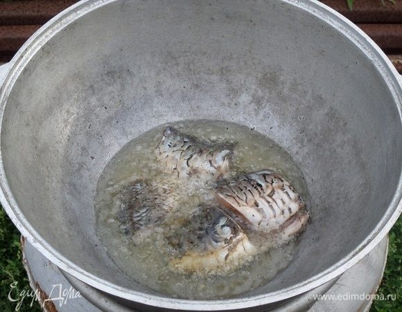 В казан наливаем 1 стакан растительного масла. Масло накаляется очень быстро. В раскаленное масло осторожно закладываем куски рыбы. Обжариваем 2-3 минуты с каждой стороны.