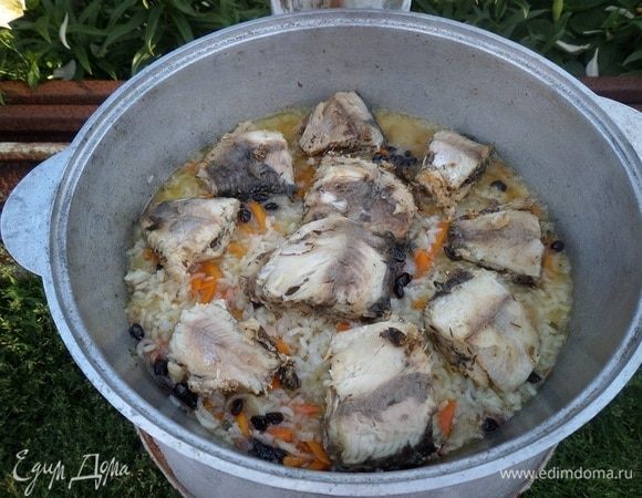 Через 15-17 минут выкладываем поверх риса куски обжаренной рыбы. Накрываем казан крышкой.