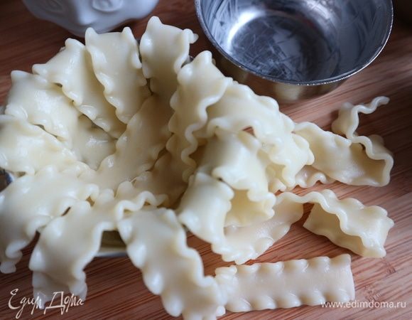 Духовку разогреть до 180°С.  Кокотницы смазать сливочным маслом. Положить в каждую кокотницу мафальдине, как показано на фото. Концы мафальдине должны свешиваться. 