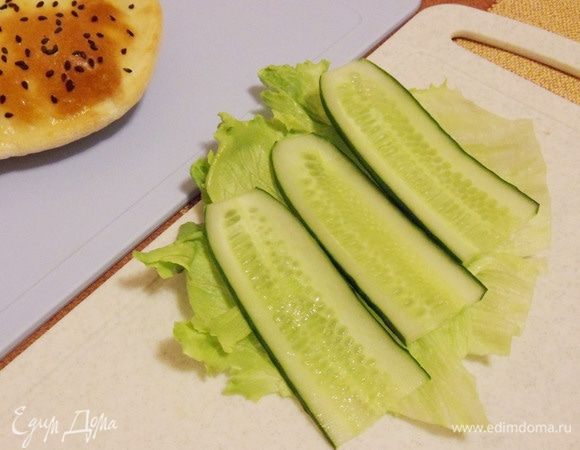 На лист салата выкладываем тонко порезанный огурец.