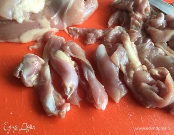 Пока варится рис, нарежьте куриное филе полосками поперек волокон.