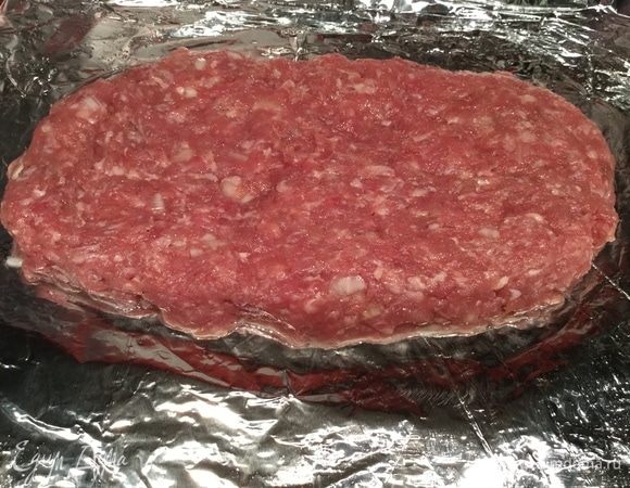 Разогрейте духовку до 180°С. Противень застелите фольгой и смажьте растительным маслом. Выложите половину фарша слоем 1,5 см.