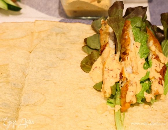 На край лаваша складываем салатный лист, рыбу, поливаем все соусом и сверху складываем нарезанные овощи.
