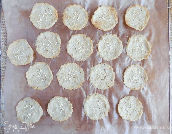 Когда крекеры будут готовы, перетащить бумагу с ними с противня на решетку и полностью остудить (горячие крекеры не получится снять с бумаги — часть теста останется на ней).