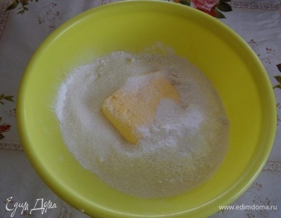 В глубокую миску просеиваем муку. Выкладываем 100 г сахара, разрыхлитель теста и сливочный маргарин.