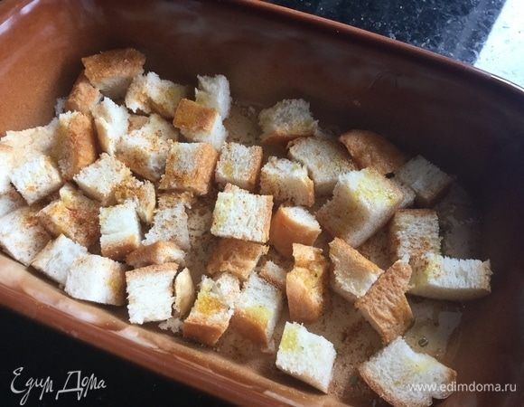 Духовку нагрейте до 200°С. Хлеб нарежьте маленькими кусочками, положите в форму для запекания, приправьте любимыми специями (у меня специи для курицы) и сбрызните оливковым маслом. Запекайте до румяной корочки около 15 минут.