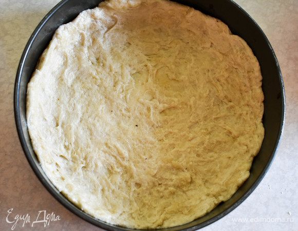 Хорошо вымесить тесто. При необходимости добавить еще муку. Тесто должно быть плотным и не прилипать к пальцам. Распределить его по форме, сфоримровав бортики. 