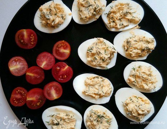 Нафаршируйте полученной начинкой яйца.
Сверху украсьте помидором.