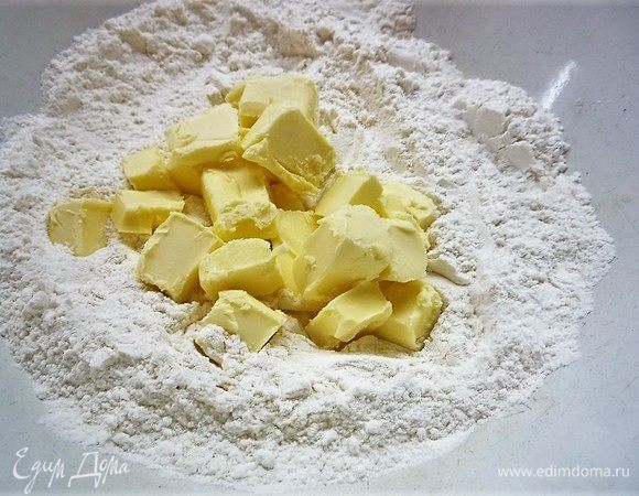 В чашке смешиваем муку и сахар. Добавляем холодное сливочное масло и перемешиваем до состояния крошки.