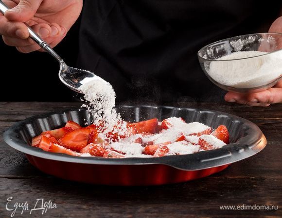 Пока тесто поднимется, приготовьте начинку. Клубнику хорошо промойте, очистите от хвостиков, нарежьте. Выложите клубнику в форму, посыпьте сахаром и крахмалом.