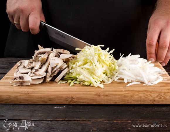 Тем временем приготовьте начинку. Нашинкуйте капусту, нарежьте мелко лук. Грибы нарежьте. 