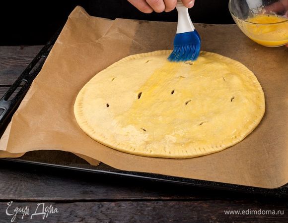 Накройте начинку вторым пластом теста. Защипните края пирога и смажьте его сверху взбитым яйцом. 