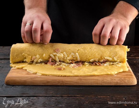 Вымесите еще раз тесто, раскатайте в тонкий пласт. Выложите начинку. Сверните тесто с начинкой в рулет и защипните края. 