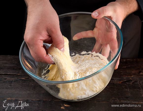 Когда опара поднимется, постепенно добавьте оставшуюся муку и вымесите тесто. Накройте тесто полотенцем и оставьте подходить еще на 15 минут.