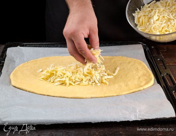Раскатайте тесто, выложите на противень, сверху распределите сыр.