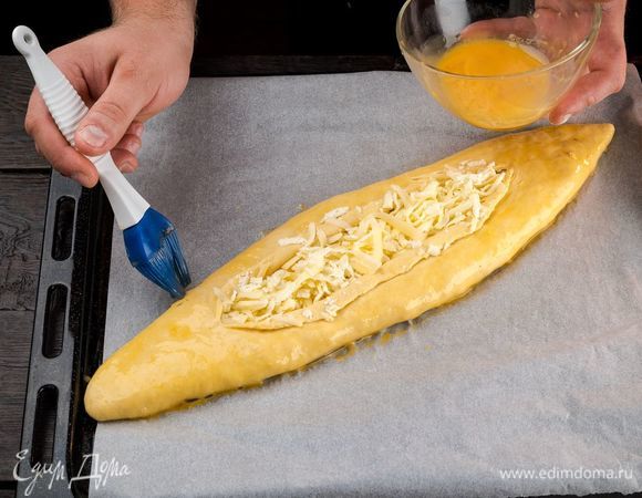 Разрежьте «лодочку» по центру вдоль, заверните края и смажьте яйцом.