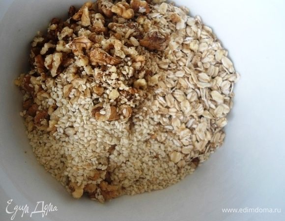 В миске смешать овсяные хлопья, кунжут, крупно порубленные орехи и специи.