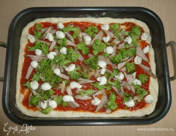 Смазать тесто соусом, выложить мясо и анчоусы. Нарвать моцареллу, разложить брокколи, посыпать сушеным чили и сбрызнуть оливковым маслом. Выпекать 25-30 минут до золотистой корочки.