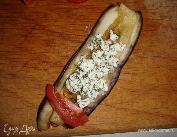 Кладем баклажан, на него кабачок, с одного края брусочек помидора, выкладываем немного творога. Заворачиваем овощи в рулетик и скалываем зубочисткой.