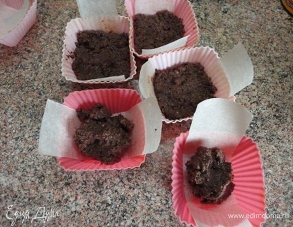 Для основы раскрошим печенье, добавим какао и растопленное сливочное масло. Все смешиваем и выкладываем в 6 формочек для кекса. Бумага нужна для того, чтобы удобнее было извлекать пирожное из форм. Распределить массу основы по дну формочек.