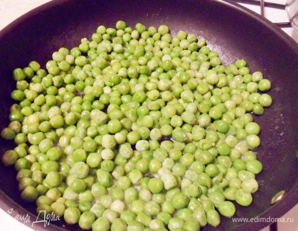 Пока тесто отдыхает, приготовим начинку. В сковороде растопить сливочное масло, выложить зеленый горошек (если горошек замороженный, то размораживать не надо). 