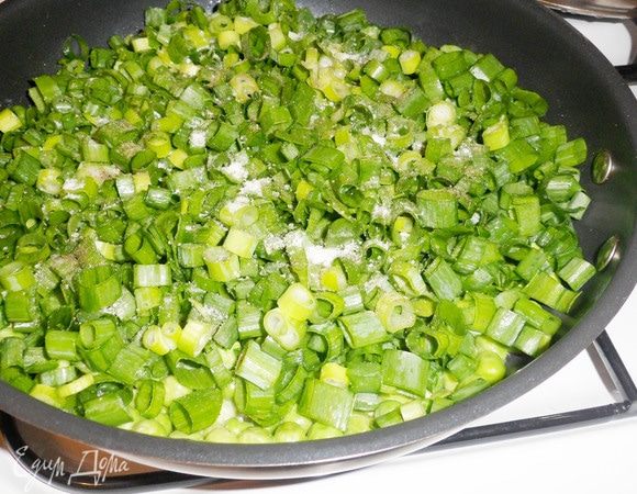 Зеленый лук (большой пучок) мелко нарезать и выложить на сковороду к зеленому горошку. Посолить, поперчить.