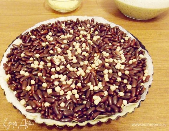 Высыпать груз, который по высоте должен перекрывать бортики теста. Для этой цели я использую смесь фасоли и гороха. Это все нужно для того, чтобы тесто в процессе выпечки не сползло с бортиков и не вздулось.