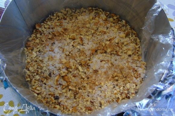 Орехи измельчите, но не сильно мелко. Форму 20 см выстелить пленкой и на дно насыпьте орехи. При желании посыпьте сахаром и корицей.