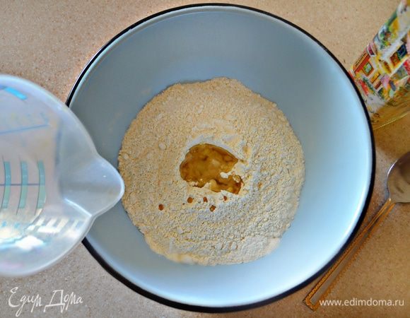 Муку смешать с солью и просеять в миску. Сделать колодец и влить растительное масло и теплую воду.