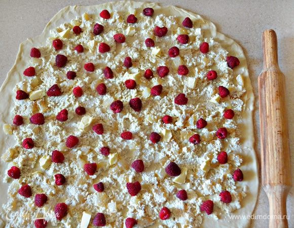 Охлажденное тесто выложить на присыпанную мукой поверхность, раскатать в прямоугольник и смазать растительным маслом. Выложить на тесто творожно-грушевую начинку, оставляя края на 2 см свободными, сверху равномерно распределите ягоды малины и кусочки сливочного масла.