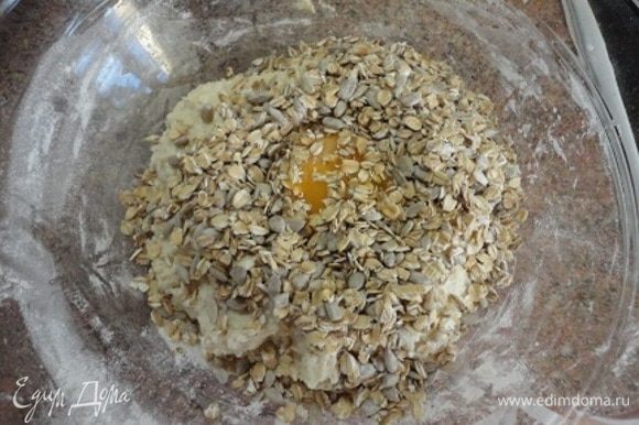 Добавьте яйцо, овсяные хлопья, семечки и вмесите их в тесто. Затем добавьте растительное масло и еще раз хорошо перемешайте.