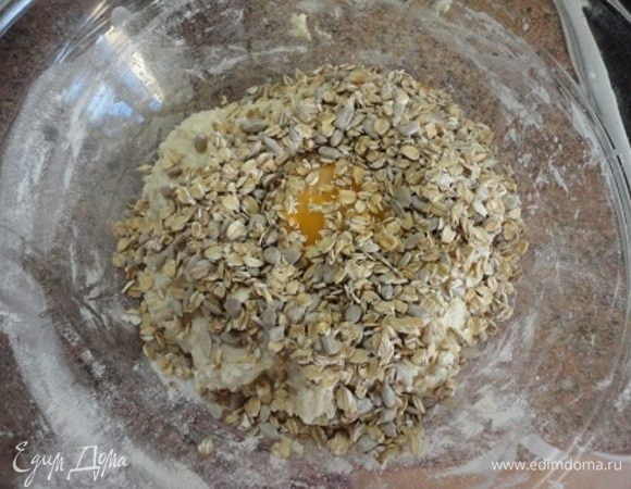 Добавьте яйцо, овсяные хлопья, семечки и вмесите их в тесто. Затем добавьте растительное масло и еще раз хорошо перемешайте.