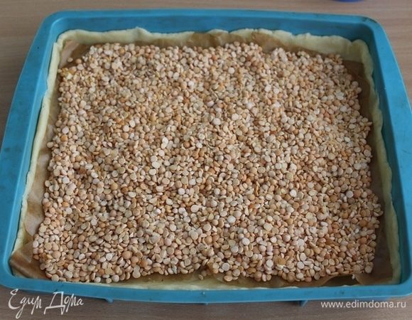 Положить сверху пекарскую бумагу, поверх которой насыпать фасоль или горох. Выпекать в заранее разогретой духовке до 180°С 10-15 минут, потом убрать бумагу с грузом и печь еще 10-15 минут. Остудить и вынуть из формы.