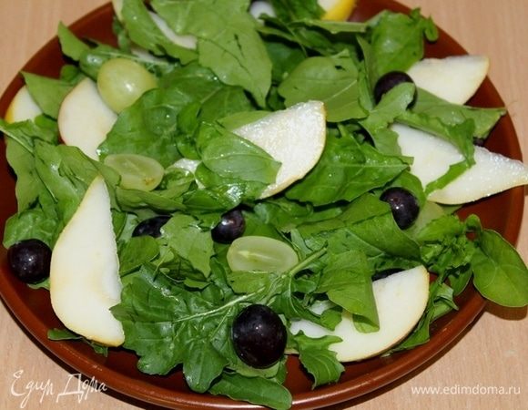 Выложить руколу, виноград без косточек, дольки груши на тарелку.