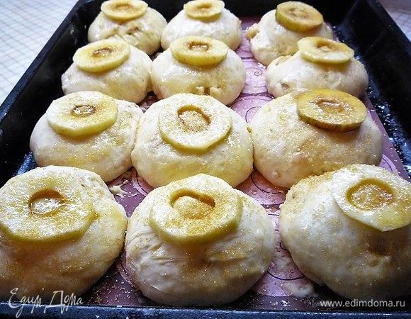 Булочки увеличились в объеме. Верх каждой булочки слегка смачиваем водой, кладем слайс яблока, сверху смазываем растопленным сливочным маслом и посыпаем коричневым сахаром.